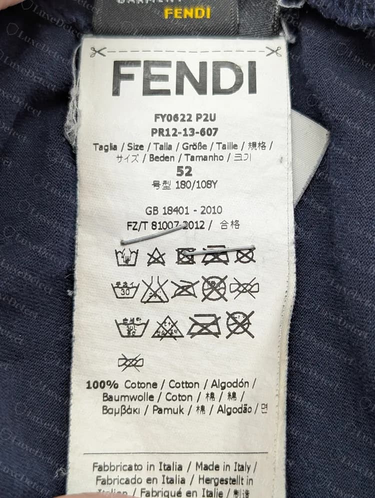 Genuine Fendi T-shirt care label: FENDI heading, style and season codes, size line, a GB 18401 - 2010 compliance line, care symbols and a multilingual composition line