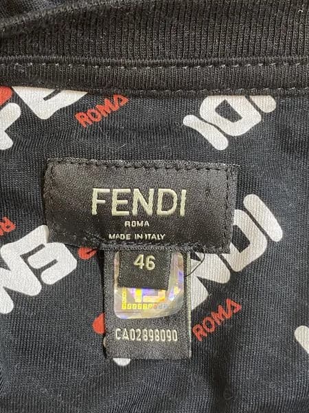 Camiseta Fendi falsificada: una pestaña de talla que cuelga de la etiqueta del cuello lleva el adhesivo holográfico y un número CA impreso, en lugar de que la pestaña con holograma esté en la costura lateral