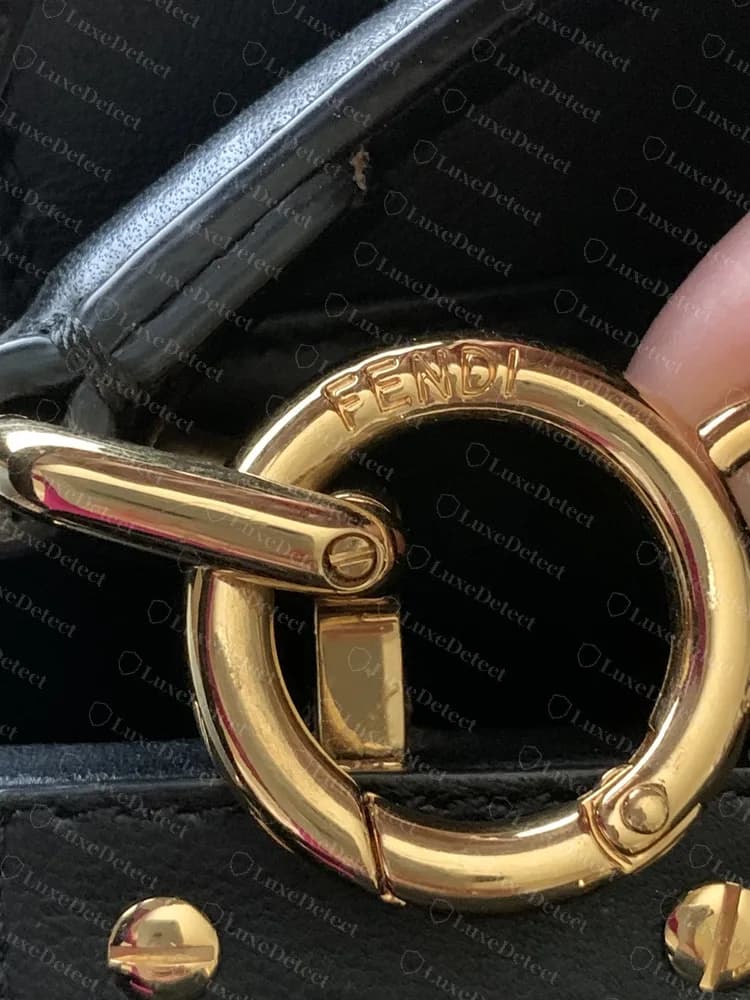 Genuine Peekaboo strap ring in polished gold tone: FENDI engraved along the curve, with a flush spring gate and matching screw-head studs on the leather below