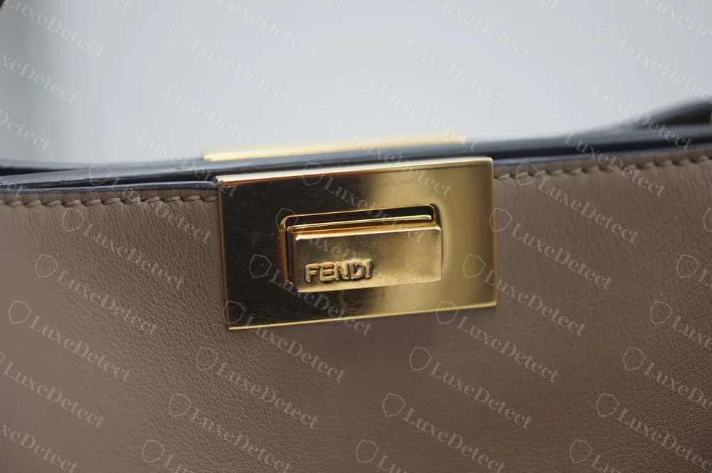 Fecho giratório de uma Peekaboo original em dourado polido, FENDI gravado na barra, numa moldura retangular limpa sobre couro liso