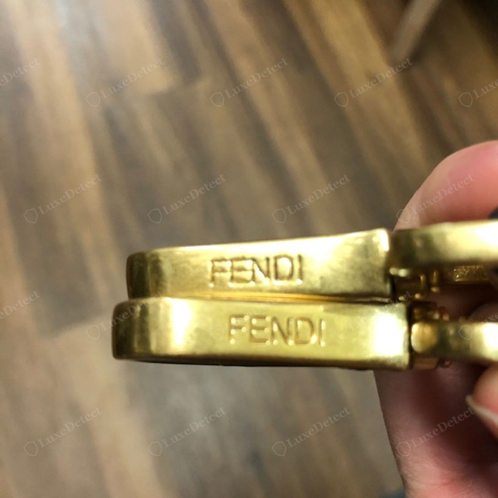 Counterfeit Fendi Baguette hardware — a lightweight or hollow buckle, a soft or shallow "FENDI" engraving, mismatched plating tones