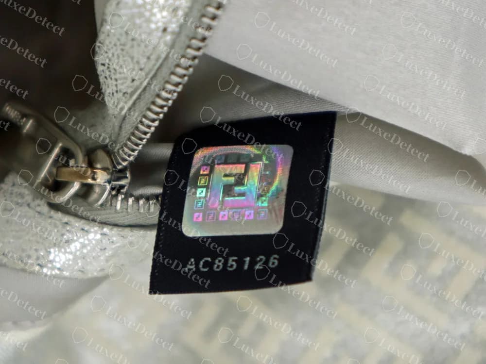 A genuine Fendi hologram tag: a black woven tab with a rainbow FF hologram and the number AC85126 printed beneath