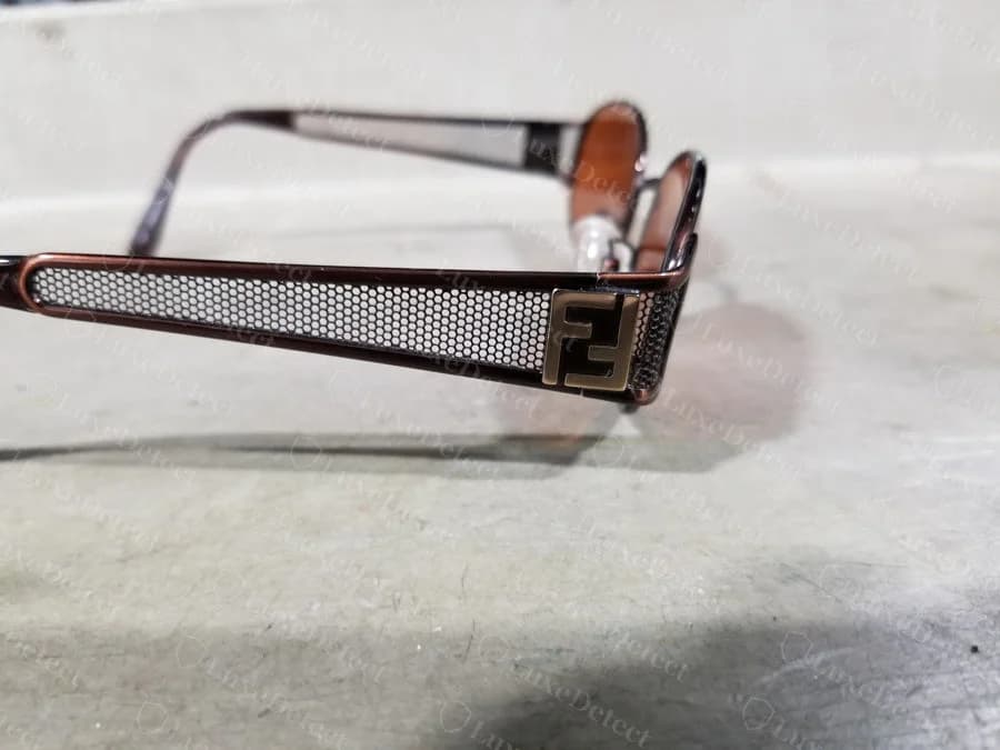Counterfeit Fendi frame with an enamel-filled FF hardware plaque mounted on a perforated mesh temple, a design associated with 1990s-2000s Fendi metal frames.