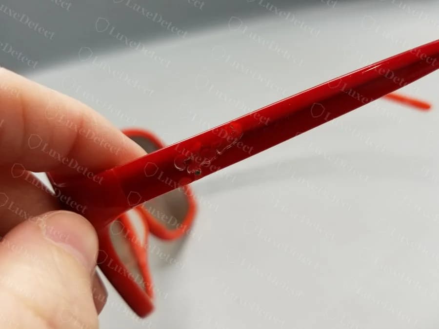 The same counterfeit pair's temple-hinge seam from a second angle, confirming the adhesive residue is not a photo artifact.