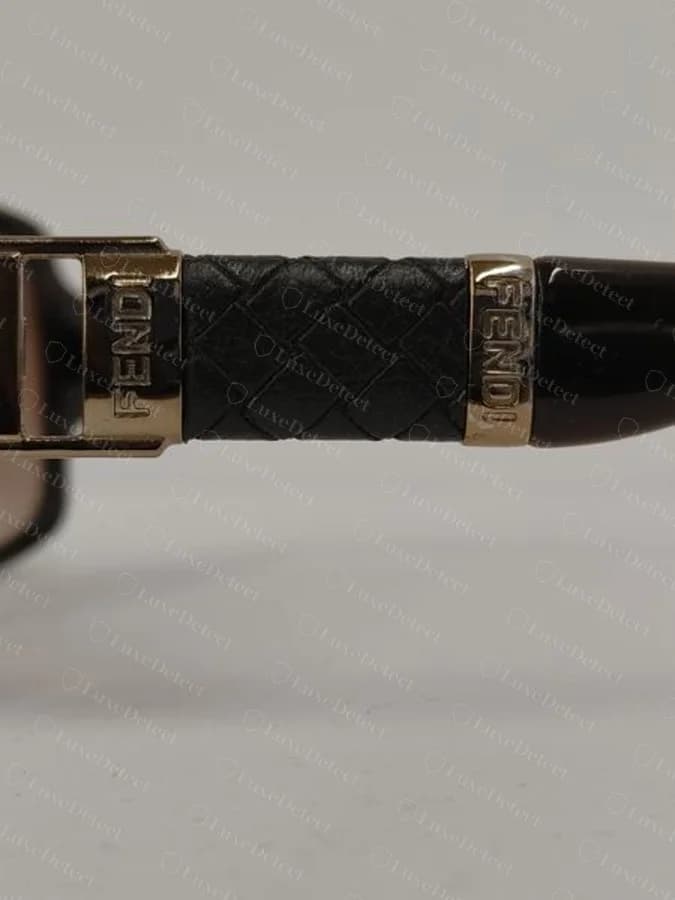 Counterfeit Fendi temple with a woven leather wrap and two separate raised "FENDI" hardware tabs; the printed model code on this pair was crisp and correctly formatted.