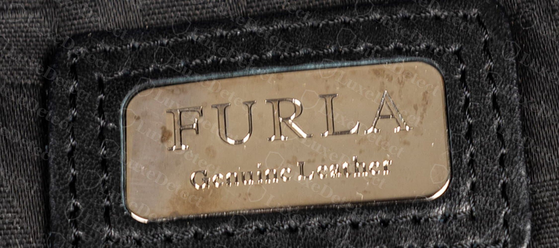 Interior tag from a bag flagged as counterfeit — wording and plate construction are close enough that this detail alone isn't decisive.