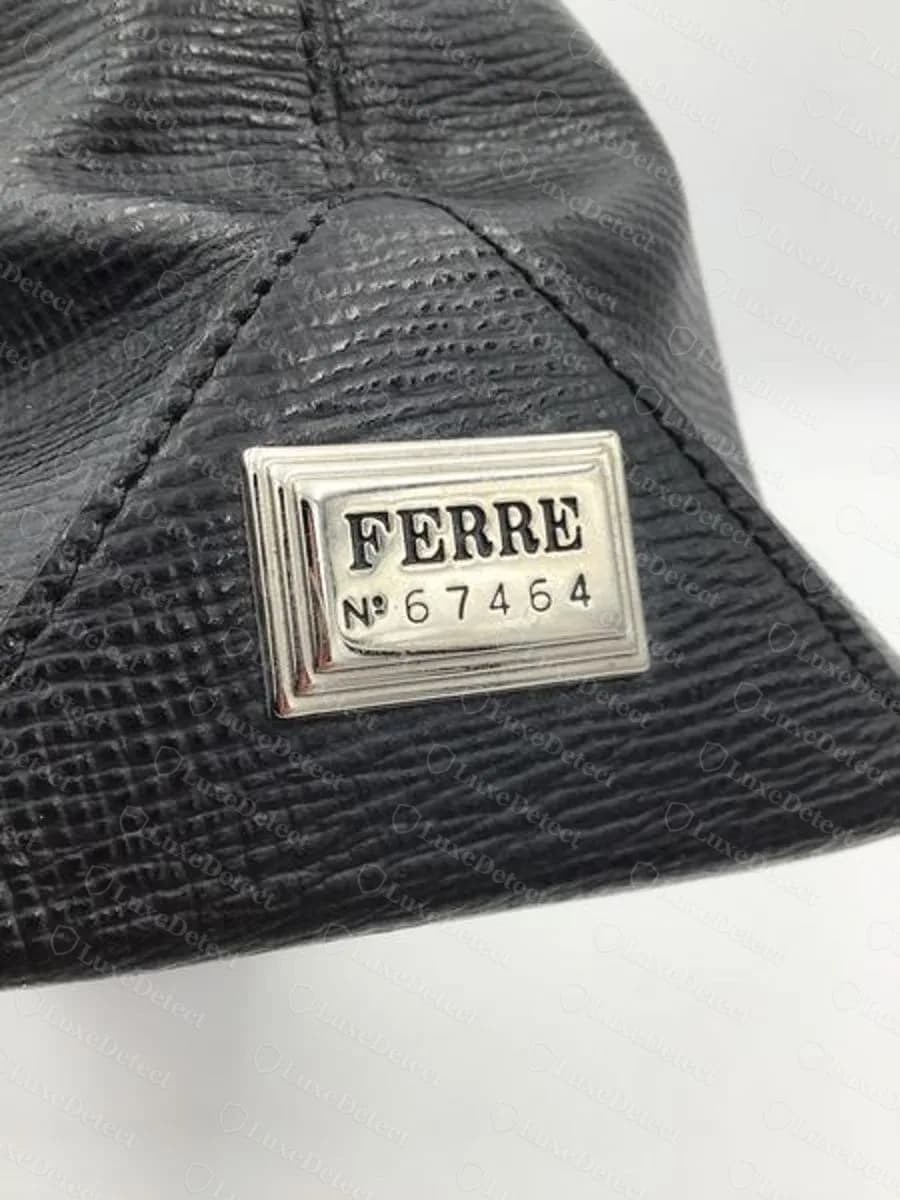 Genuine Ferré handbag: silver-tone rectangular plate reading FERRE with N and a five-digit number beneath, set on the corner of a black textured leather bag