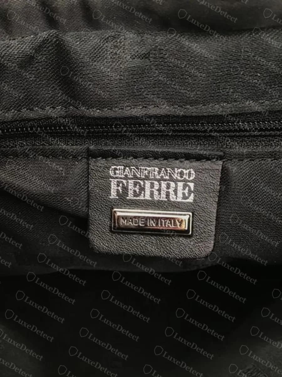 Genuine Ferré handbag interior: black leather tab above a zip, printed GIANFRANCO FERRE in white capitals with a small metal MADE IN ITALY plate beneath