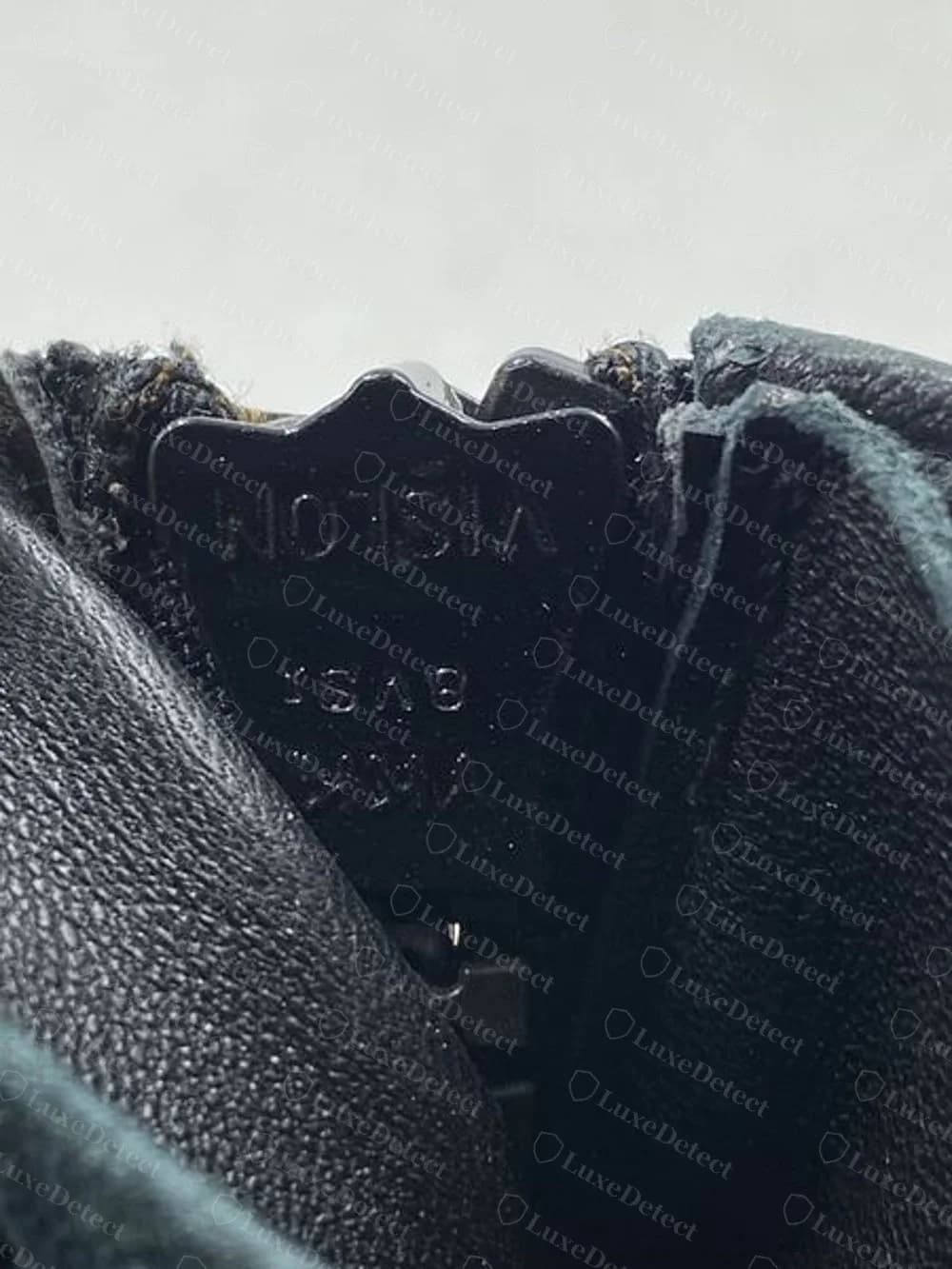 Cursor de cremallera de plástico negro original de Giuseppe Zanotti moldeado con VISLON, con las letras apareciendo al revés, entre paneles de piel negra