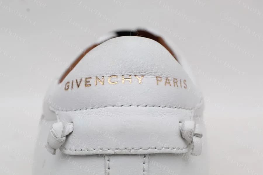 Linguetta del tallone di una Givenchy Urban Street originale con GIVENCHY PARIS in oro e due piccoli anelli annodati
