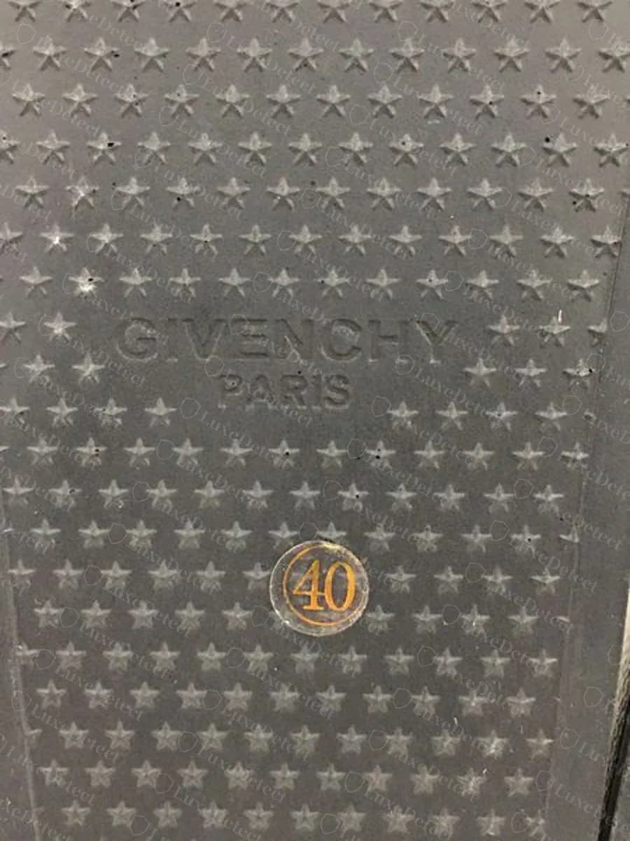 Suela de una slide Givenchy falsa con una pegatina redonda dorada de talla, 40, debajo del logo GIVENCHY PARIS