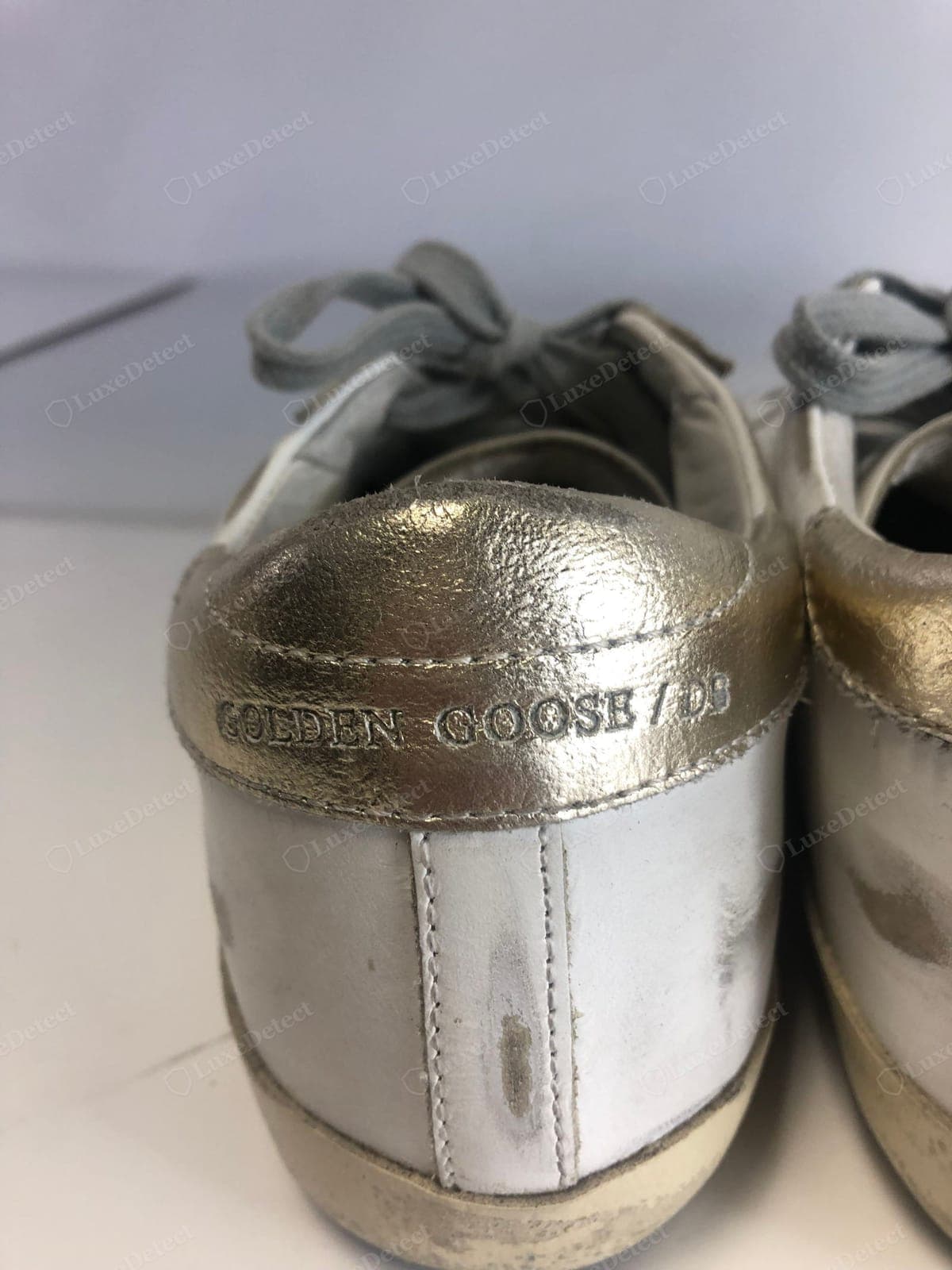 Linguetta del tallone Golden Goose originale: “GOLDEN GOOSE” e una barra stampati sul contrafforte metallico del tallone, applicati in modo pulito con lettere nitide