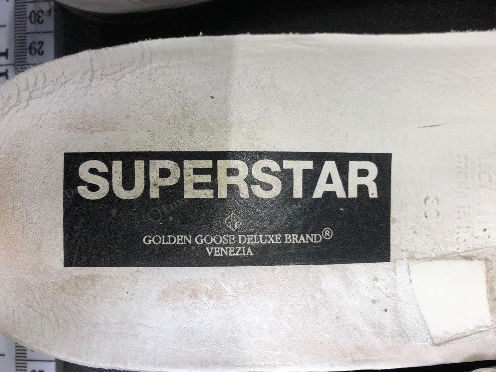 Semelle intérieure Golden Goose authentique : le nom du modèle « SUPERSTAR » au-dessus de « Golden Goose Deluxe Brand / Venezia » dans l'impression ancienne, nette et correctement orthographiée