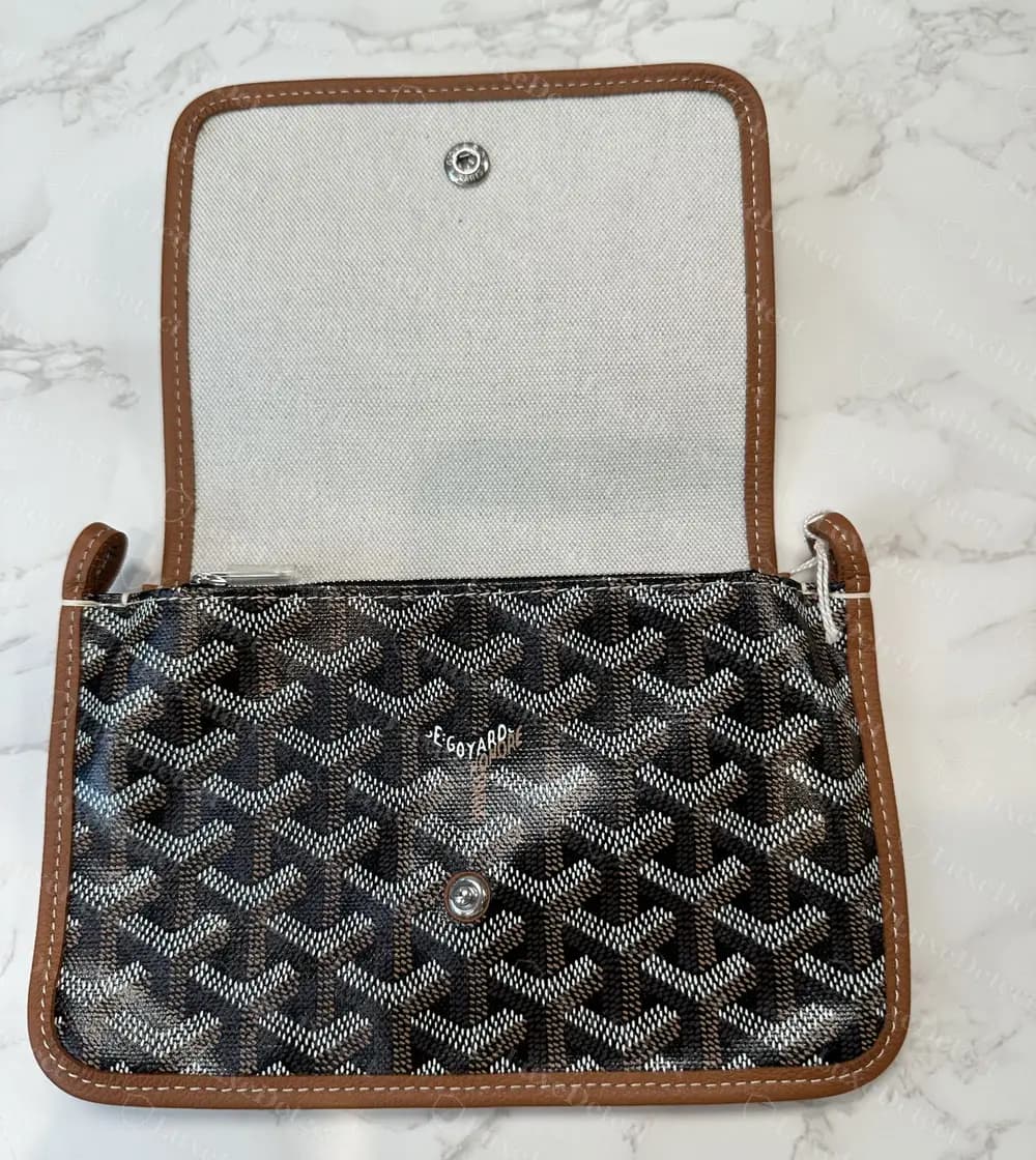 Genuine Goyard Plumet pocket wallet opened: the underside of the flap is lined in woven canvas with only the snap socket set into it, above the black Goyardine body and tan leather piping