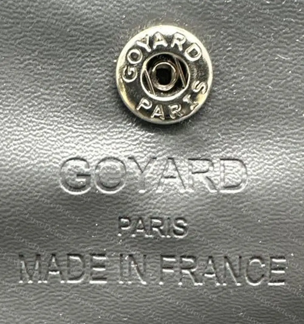 Counterfeit Plumet-style flap wallet: the underside of the flap is smooth grey leather with a GOYARD PARIS MADE IN FRANCE heat stamp directly below the snap, in plain sans-serif letters