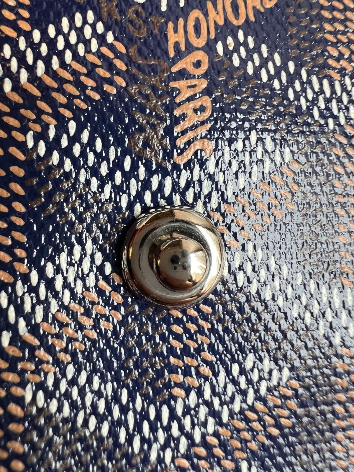Genuine Goyardine — hand-painted white Y-and-dot chevron on navy with the tan "GOYARD / ST HONORÉ / PARIS" address print, the linen weave texture showing through the coating and slight irregularity in the painted elements