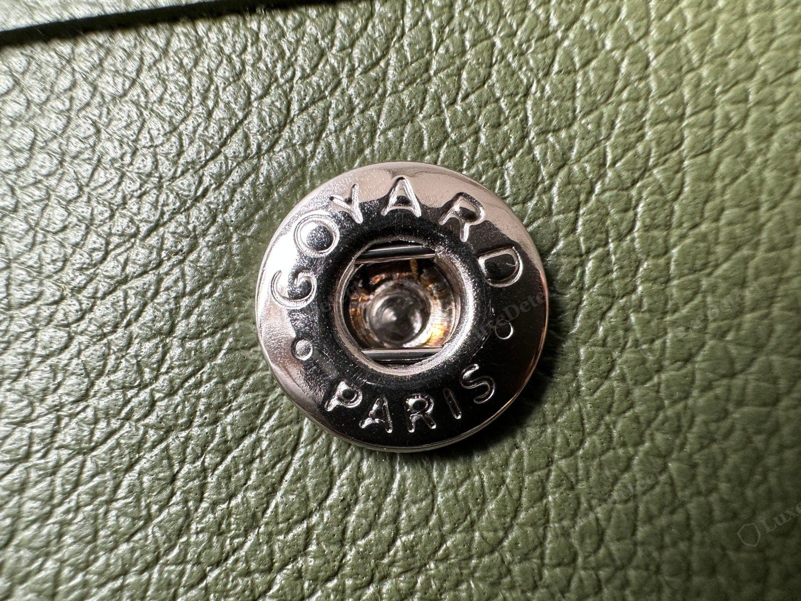 Genuine Goyard interior-pocket snap — silver, engraved "GOYARD · PARIS" in the brand's hand-drawn capitals around the rim, set cleanly into pebbled calfskin