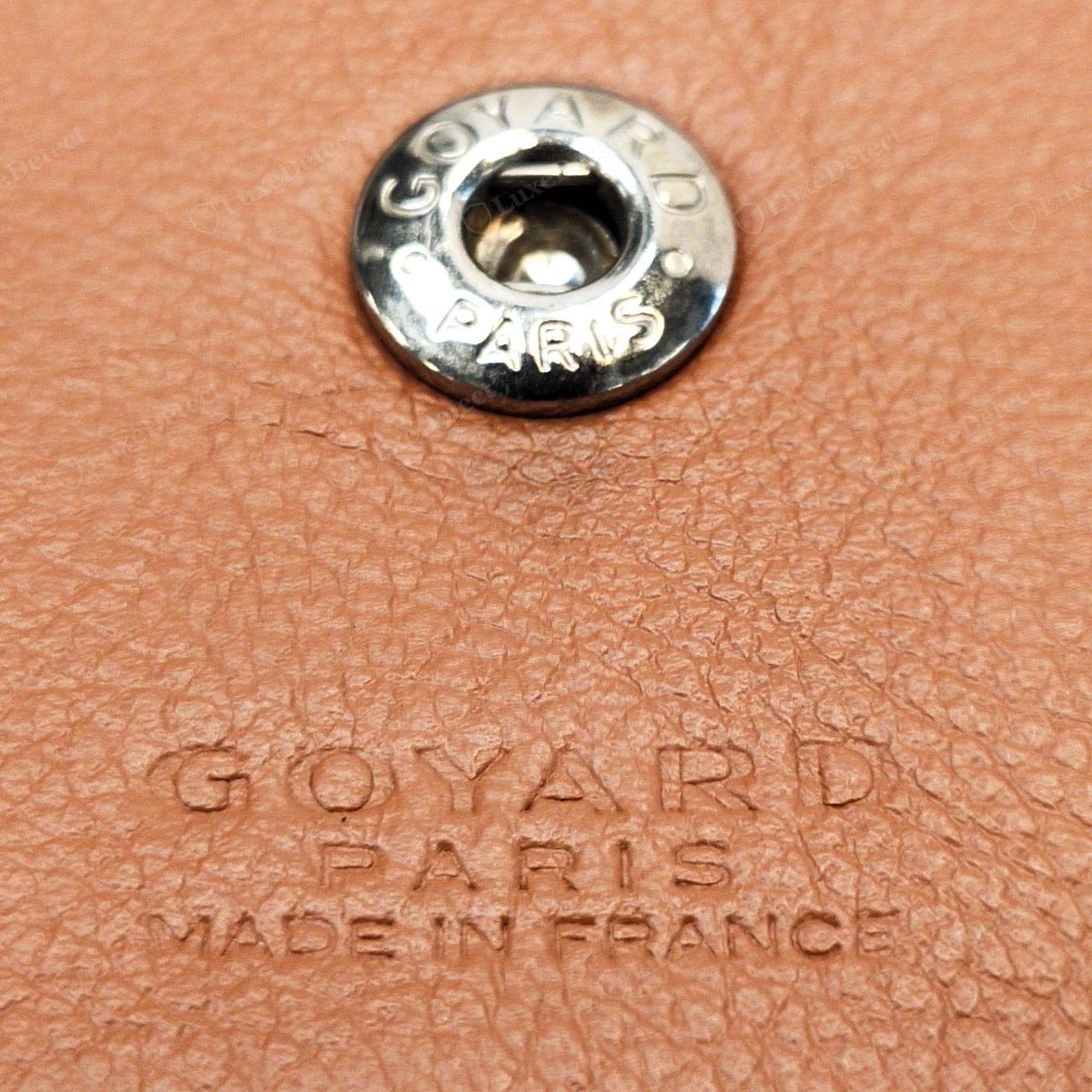 Genuine Goyard interior — the snap stamped "GOYARD · PARIS" around its rim in the house's hand-drawn caps, above a blind-embossed "GOYARD / PARIS / MADE IN FRANCE" on the leather tab