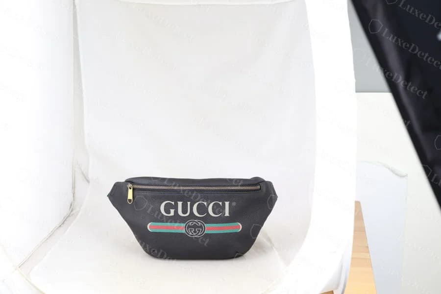 Genuine GG-print pebbled-leather Gucci belt bag, showing the printed "GUCCI" wordmark and green-red-green web stripe on a fine-grain pebbled leather base