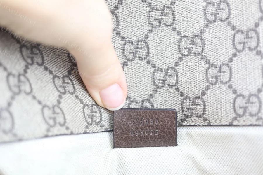 Genuine GG Supreme canvas monogram close-up with a small leather serial tab pressed against the woven canvas lining, numeric code evenly stamped