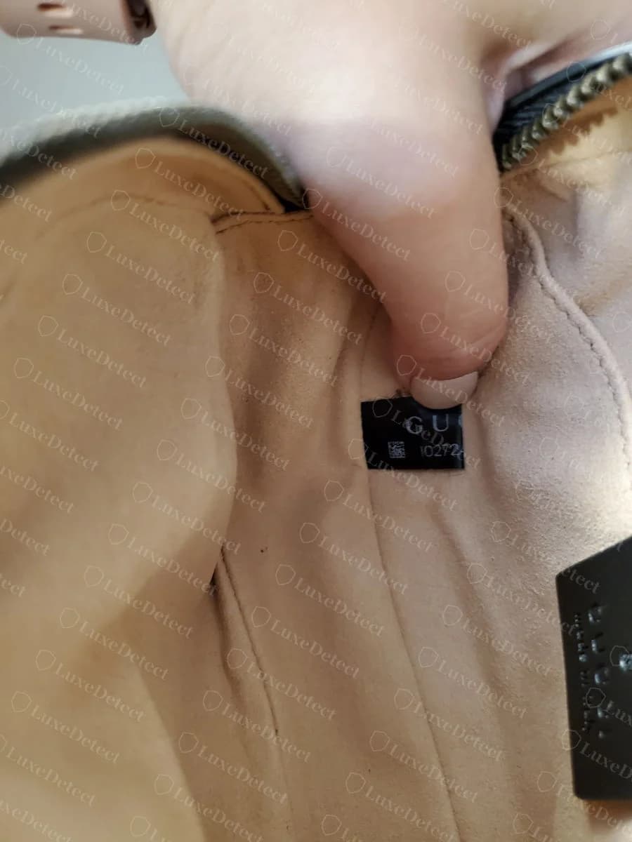 Genuine Gucci woven satin interior tag showing the QR-style micro-code above a numeric string, sewn into the lining seam