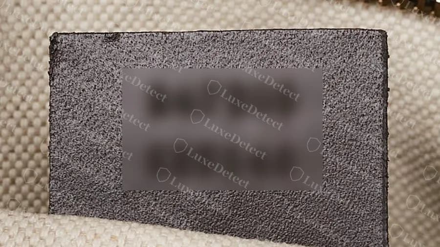 Genuine modern leather serial tag with a stamped two-line number; the digits are blurred