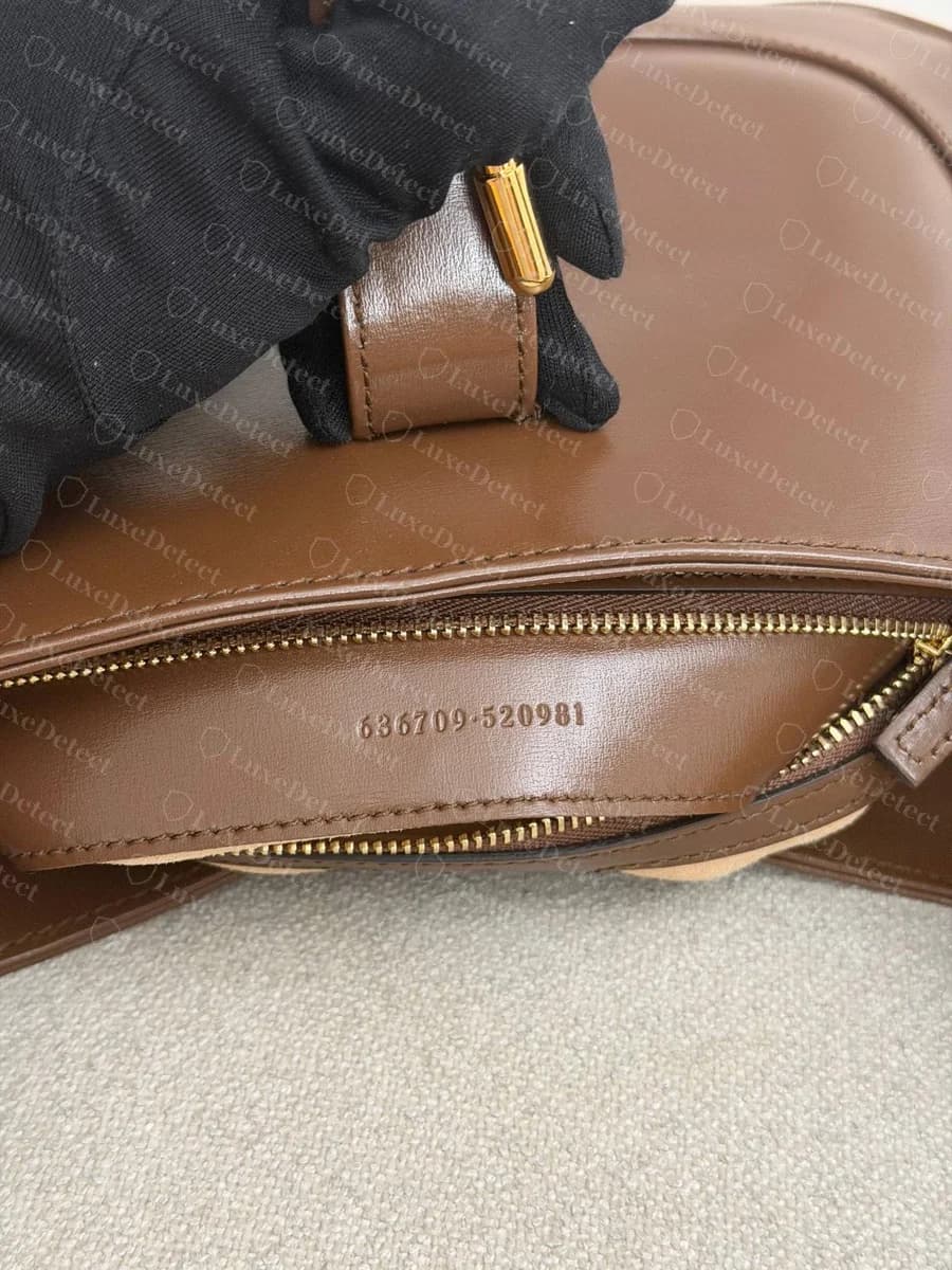 Genuine Gucci Jackie 1961 serial stamp: "636709-520981" in small, evenly spaced digits pressed lightly into the brown leather strip beside the zip