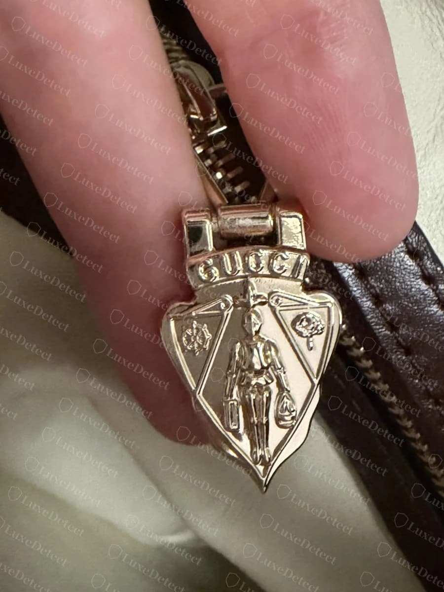 Tirette de fermeture éclair d'un Gucci Jackie 1961 contrefait : un grand écusson Gucci en forme de blason avec un chevalier, en or champagne pâle