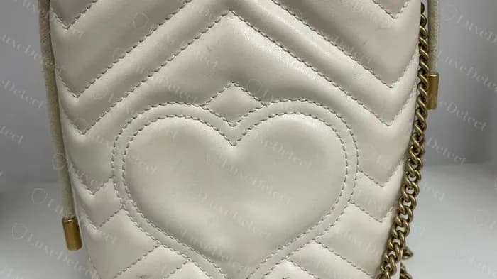 GG Marmont mini bucket genuino en piel marfil, acolchado en chevron con un motivo de corazón en el panel lateral y un cordón de cuerda