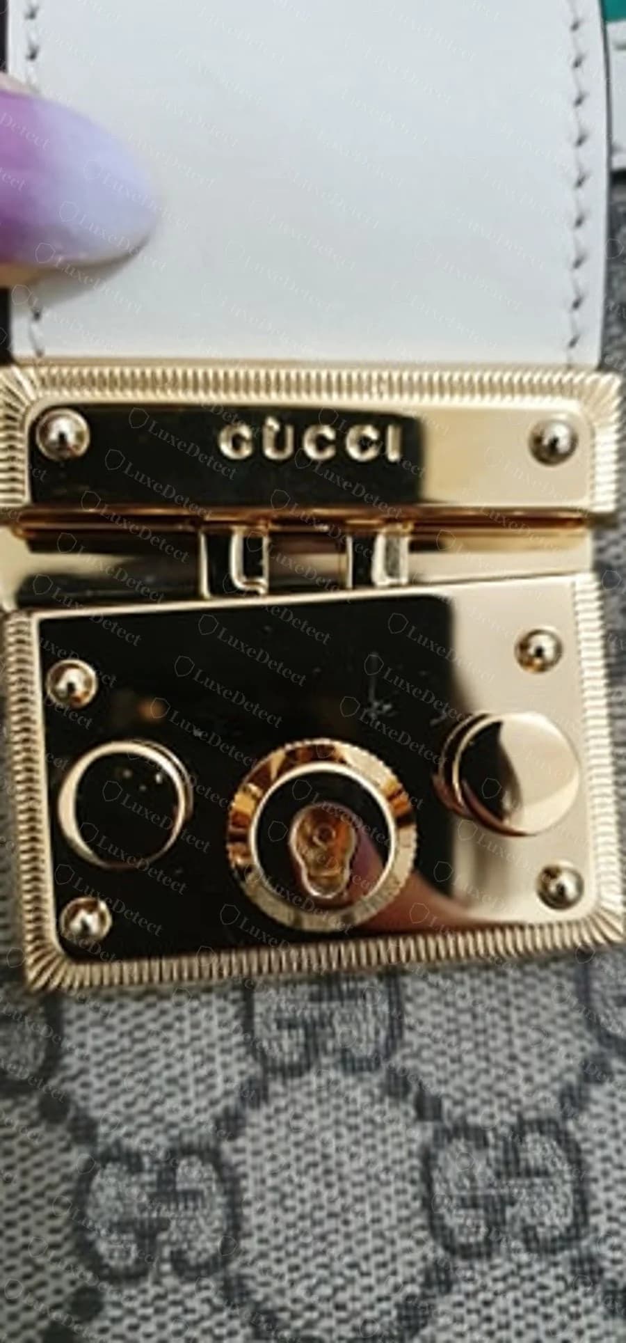 A second genuine lock plate on a different Padlock bag, confirming the same knurled border and engraving depth across colourways