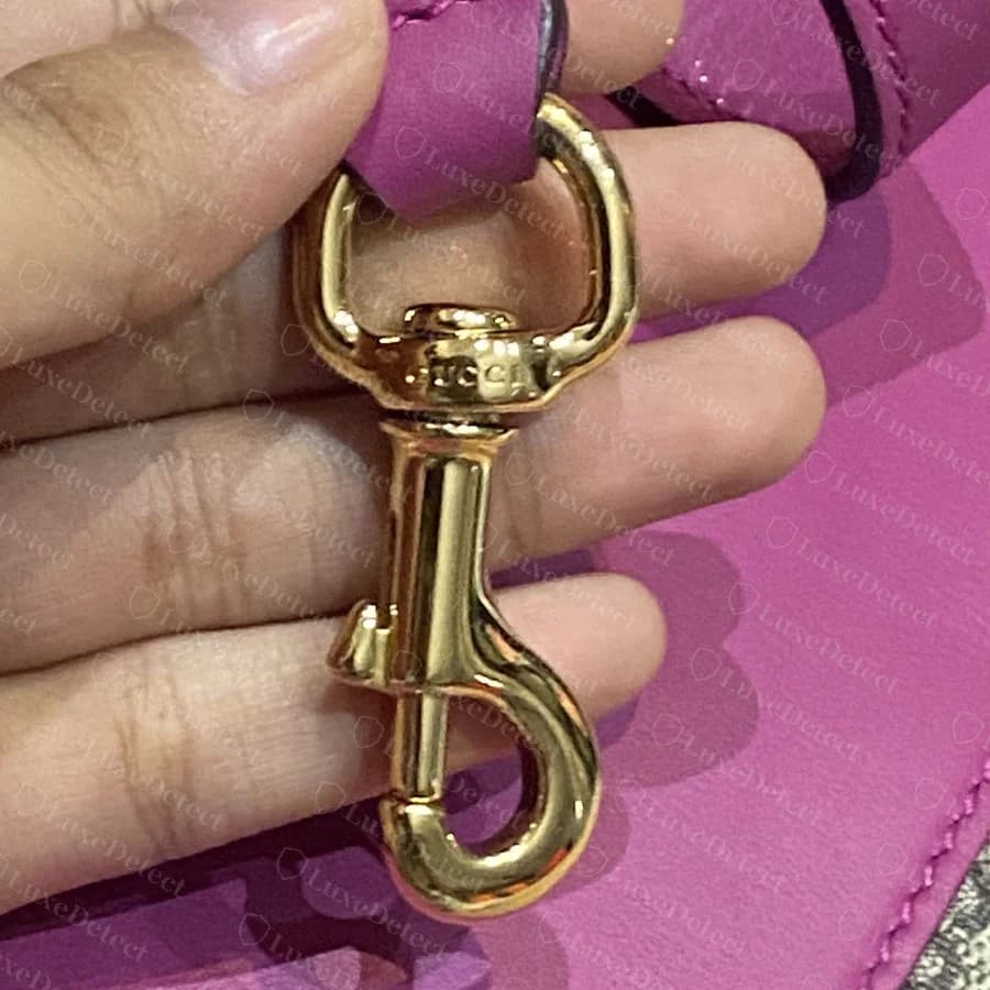 Genuine "GUCCI" engraving on a strap swivel-hook clasp, in the same small serif lettering as the lock plate