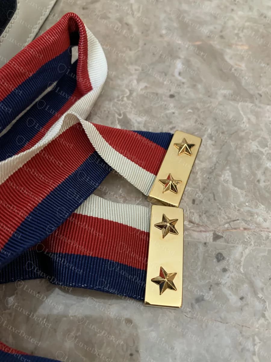 Genuine Sylvie web shoulder strap ends, gold-tone tabs with crisp raised stars clamping the red, white and navy web