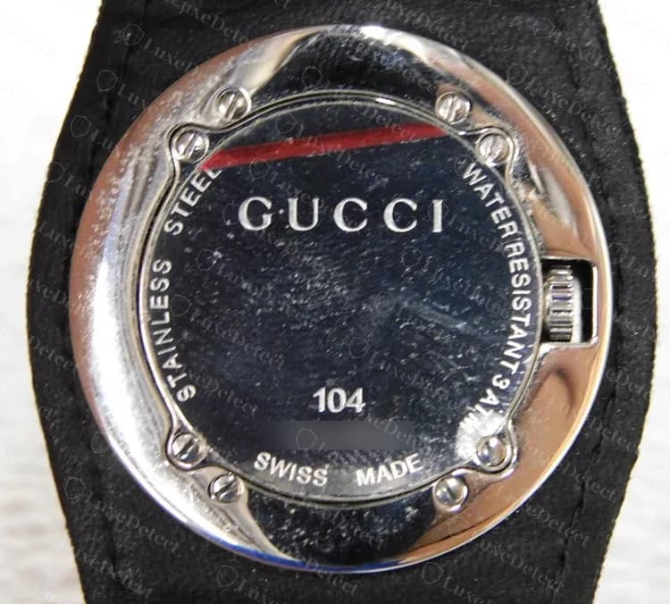 Fondo de un Gucci 104 original: GUCCI, stainless steel, water resistant 3 ATM, modelo 104 y Swiss Made alrededor del borde, número de serie difuminado