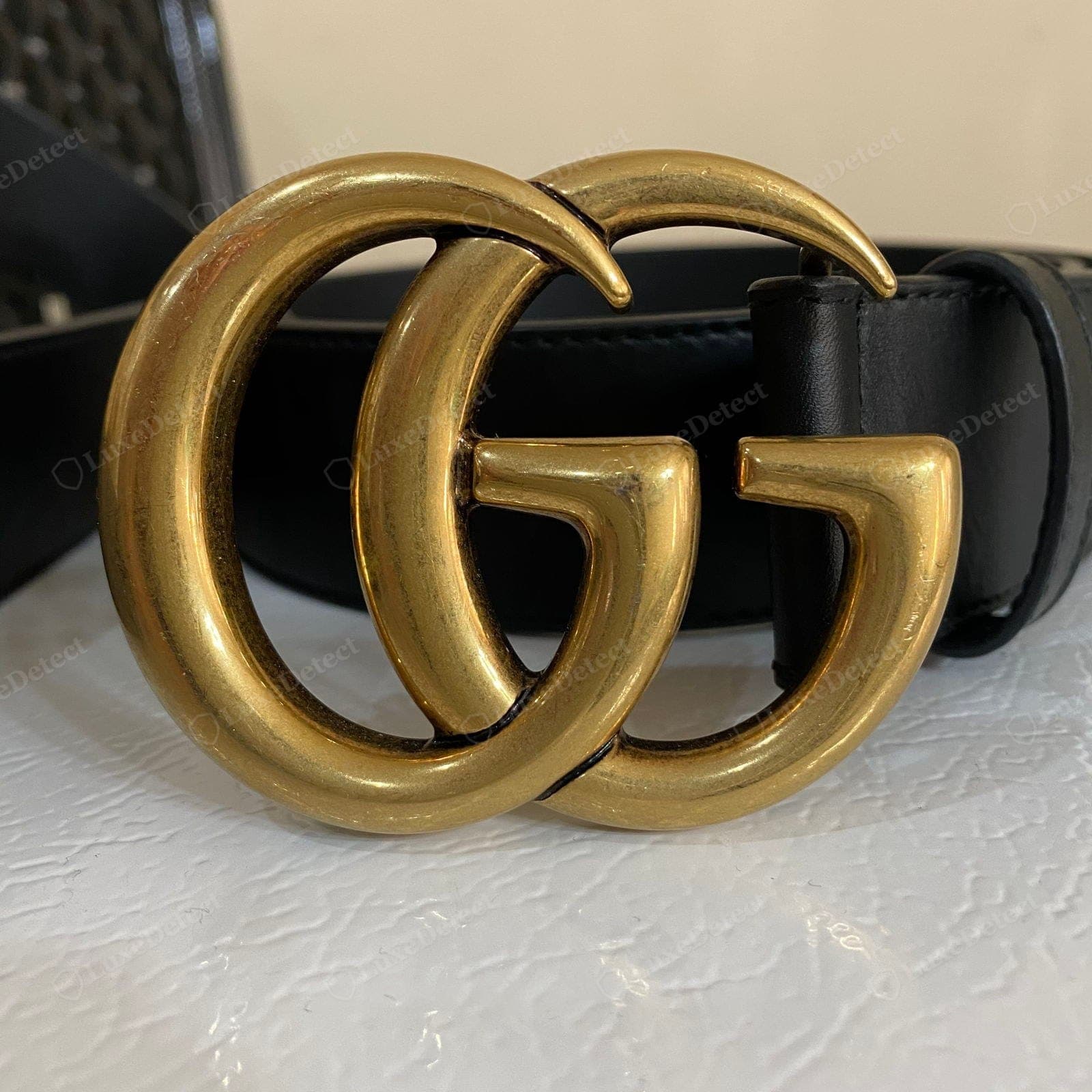 Counterfeit Gucci belt Double-G buckle — the G overlap wrong or uneven, a light hollow casting, thin brassy or mirror plating