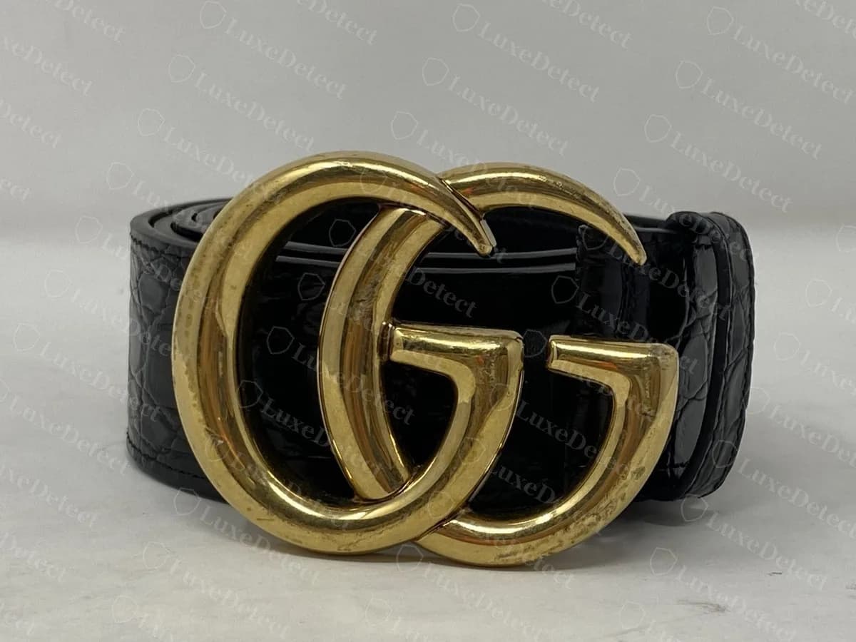 Hebilla de un cinturón Marmont original sobre una correa negra con relieve, con un acabado dorado amarillo más brillante