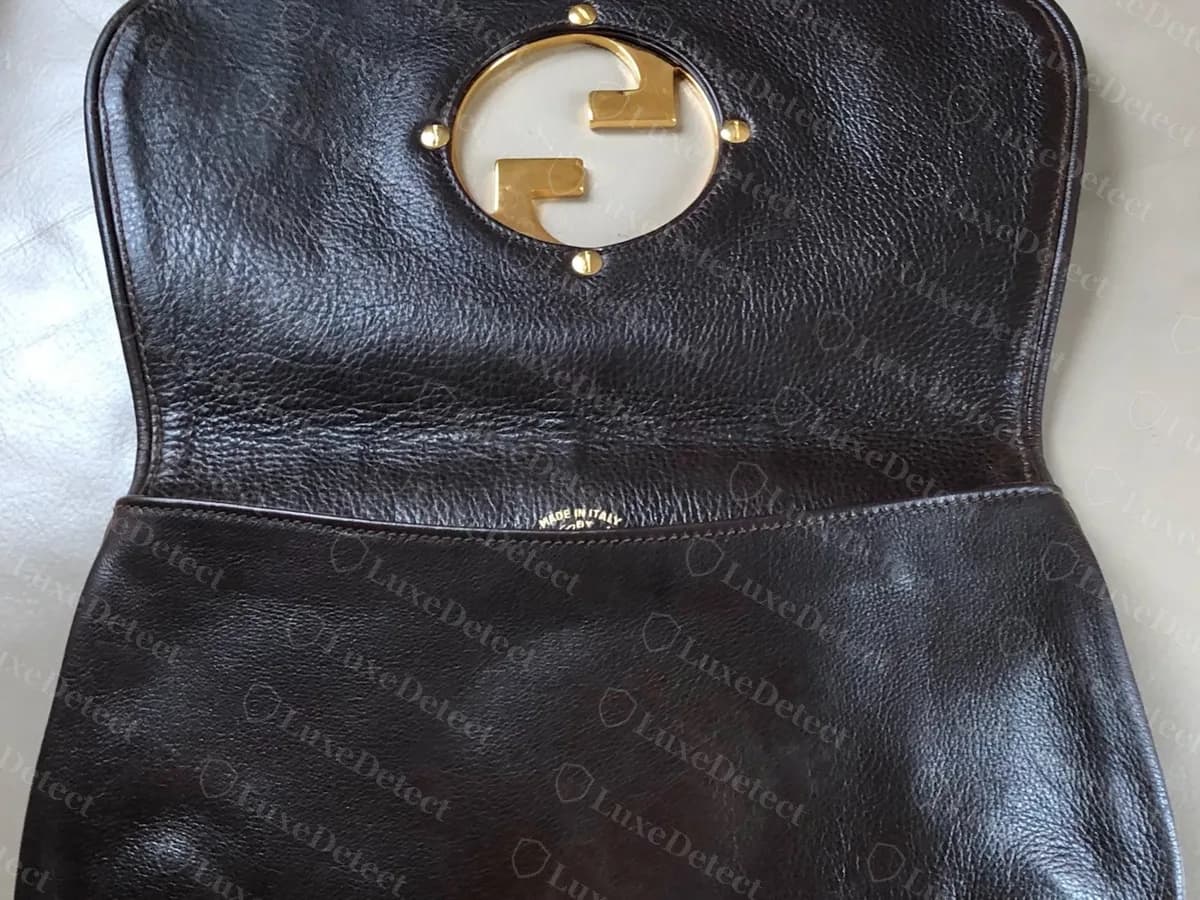 Underside of a genuine vintage Blondie flap: the back of the GG disc set over a round cut-out with four small studs, and a small stamp on the inner panel below
