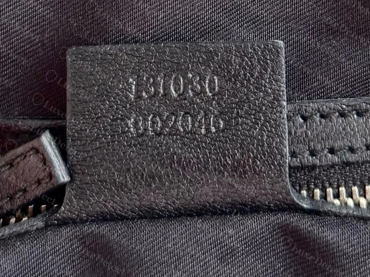 Genuine Blondie bowler interior leather tag with a two-line code stamped on it, 131030 over 002046, beside the zip