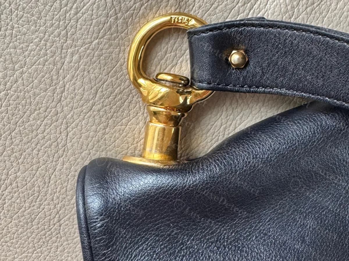 Genuine vintage Blondie strap end: a gold-tone swivel hook on a cylindrical post, with a stud holding the leather strap