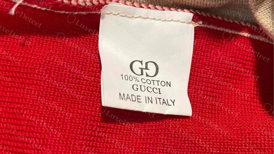 Gefälschtes Gucci Strickteil: ein kurzes schlichtes weißes Etikett mit GG, 100% cotton, Gucci, Made in Italy statt eines mehrsprachigen Pflegeetiketts