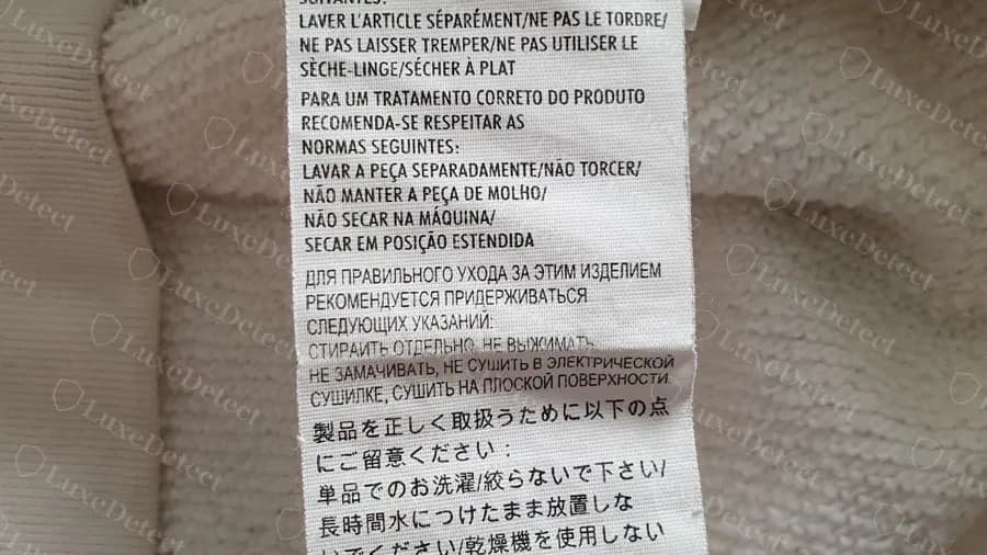 Etiqueta de cuidado de una sudadera Gucci original: una etiqueta blanca larga con las mismas instrucciones repetidas en muchos idiomas