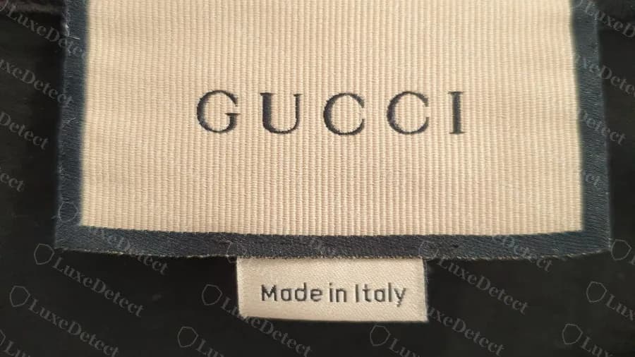 Camiseta Gucci original: etiqueta tejida del cuello en crema y con textura acanalada, con borde oscuro, y una pequeña subetiqueta blanca Made in Italy debajo