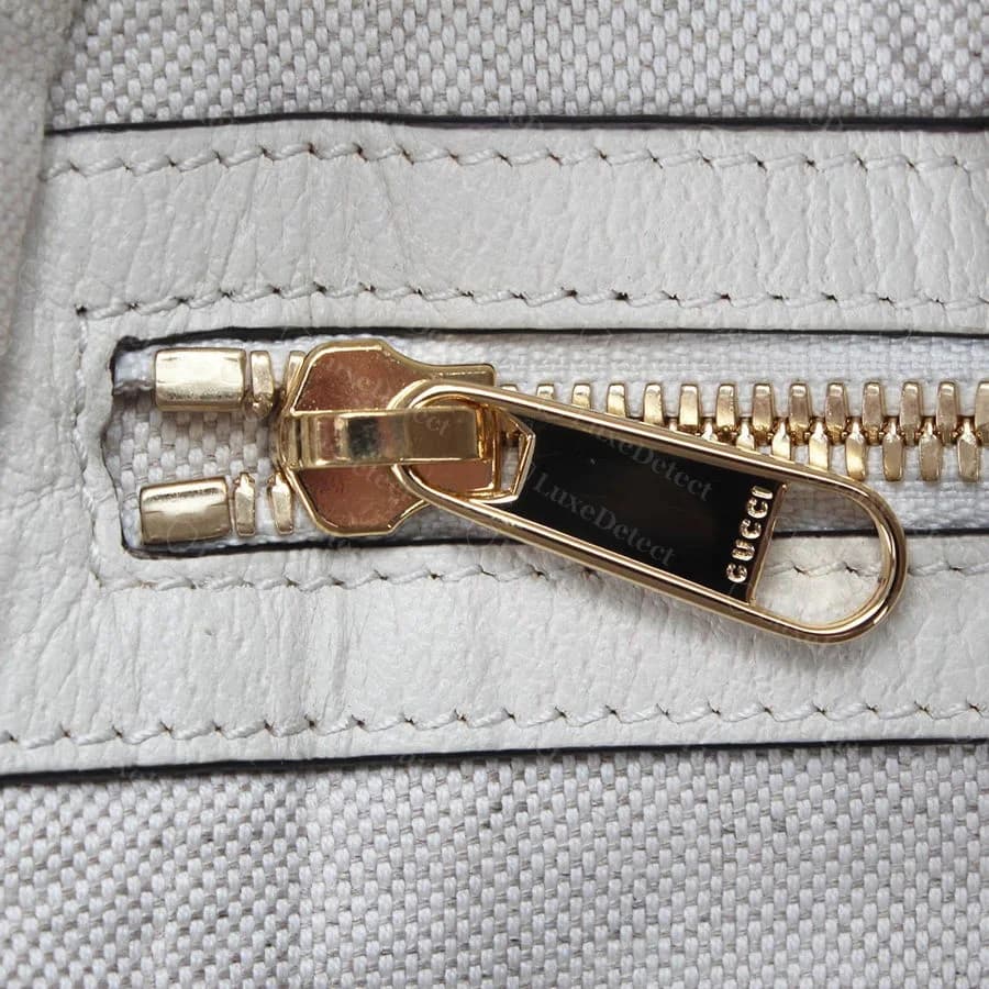Authentic Gucci zipper pull stamp, GUCCI evenly struck in the metal with consistent letter height and spacing