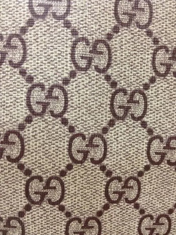 Counterfeit GG Supreme canvas close-up — the coarse woven basketweave texture of the base fabric visibly showing through a thin coating, giving the surface a fuzzy fabric feel instead of a smooth coated one