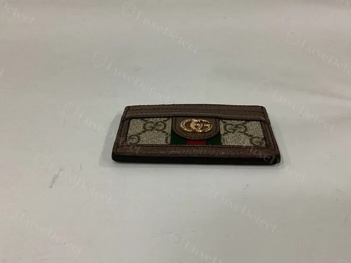 Authentic GG Supreme canvas close-up on a Gucci Ophidia card case — a smooth, tightly coated surface with the interlocking-GG print sitting crisp and flat, minimal fabric weave visible through the coating