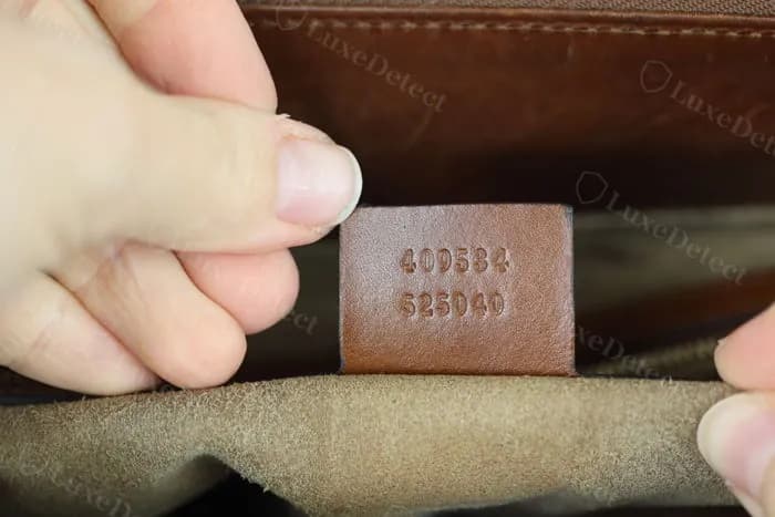 Authentic Gucci interior serial stamp — a six-digit style number over a six-digit supplier code, evenly embossed into the leather tab