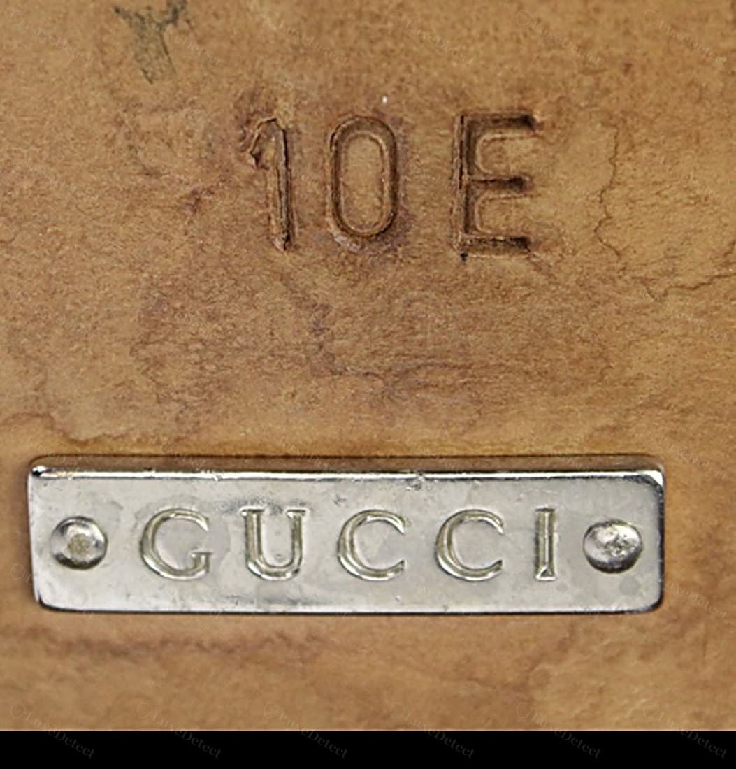 Genuine Gucci interior code plaque — a metal "•GUCCI•" name plaque cleanly engraved in the house serif, set flat with two neat rivets, the size "10 E" branded crisply into the leather above