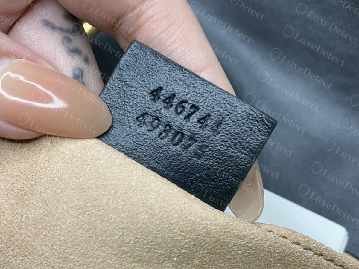 Étiquette de faux Marmont portant 446744 au-dessus d'un second numéro qui semble être 493075, en partie caché par un doigt