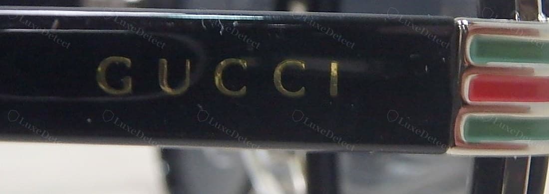 Counterfeit Gucci temple — the exterior "GUCCI" print and web-stripe inlay on a fake frame; check the interior string against this side, since fakes often get the outside closer than the inside