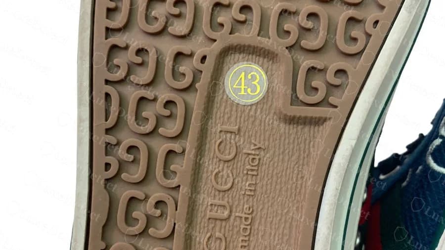 Suela de una Gucci Tennis 1977 falsa: un adhesivo redondo amarillo sobre gris con el "43" en el panel de la suela, encima de las letras GUCCI