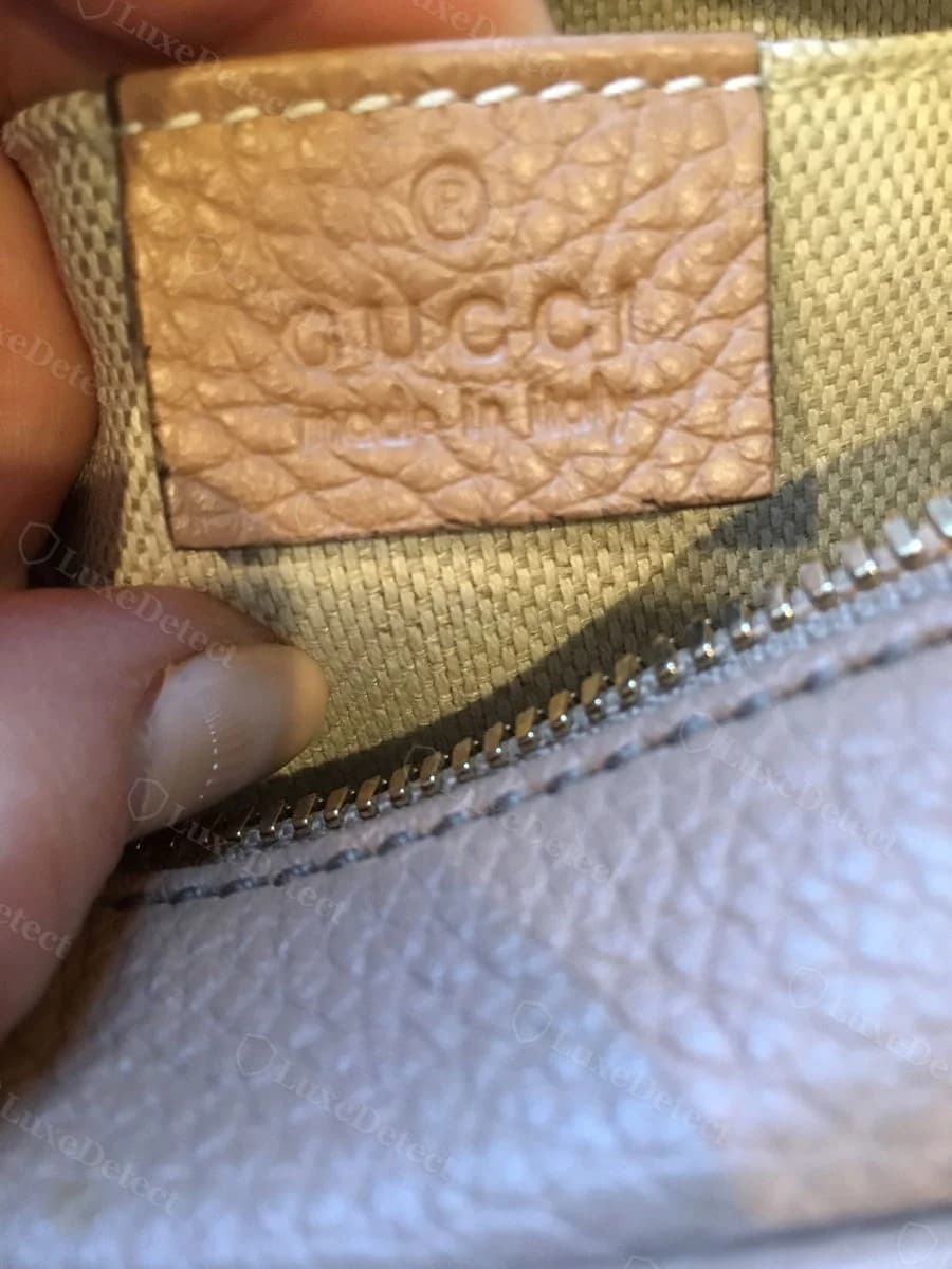 Authentic Gucci Soho Disco interior leather stamp, tan leather panel reading GUCCI made in Italy with a circled-R trademark mark above the wordmark